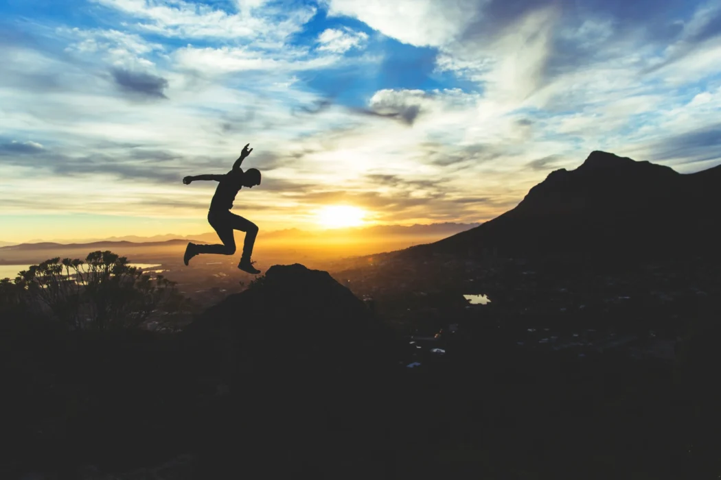 A person jumping off rocks with mountain environment in the background