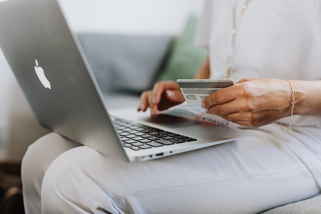 E-Commerce someone with a credit card in one hand and typing on a laptop with the other hand