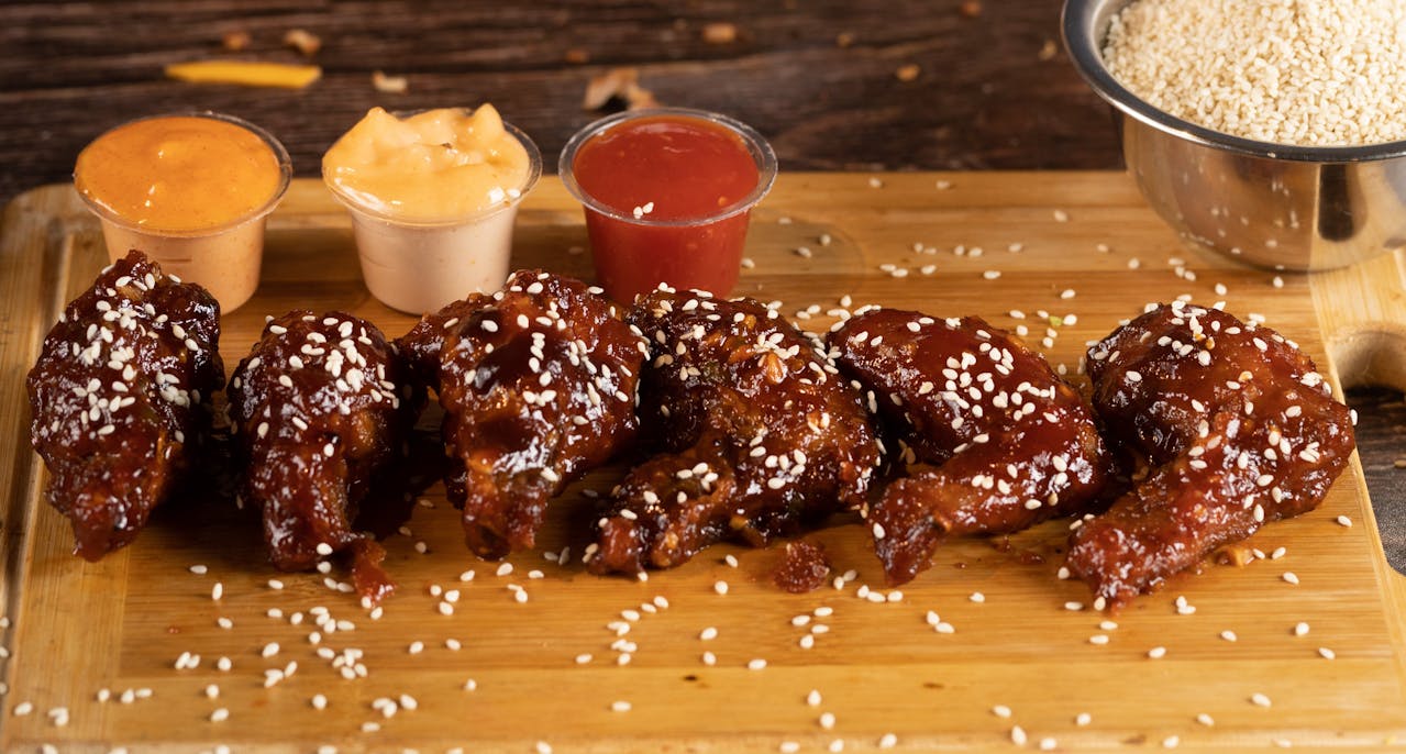 Chicken wings on a board with dipping sauces on the side